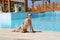 Smiling woman sitting near swimming pool