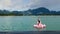 Smiling Woman Sitting on Pink Floating Flamingo on Blue Lake with Mountain