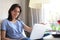 Smiling woman sitting on sofa with laptop computer and chating with friends