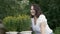 Smiling woman sniffing yellow flowers in pots in summer garden. Happy woman posing to camera in garden with blooming