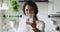 Smiling woman standing in home kitchen holding glass of water