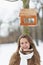 Smiling woman standing under bird feeder in winter park