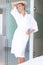 Smiling woman standing in white bathrobe