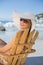 Smiling woman in straw hat relaxing in deck chair on the beach