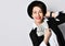 Smiling woman in stylish hat and black jacket pops up from the corner shows a fan of dollars she holds in her hand