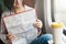 A smiling woman in a suburban train studies the map and smiles.