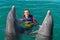 Smiling woman swimming with dolphins in blue water