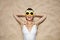 Smiling woman in swimsuit and pineapple glasses laying on sand