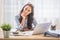 Smiling woman with titled head leaned on her hand sitting at her office desk