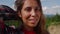 Smiling woman touching hair with hand. Female hiker hiking in summer mountains