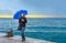 Smiling woman with umbrella on stormy sea raining horizontal background