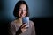 Smiling woman using cellphone in darkness at night