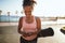 Smiling woman walking on a promenade with her yoga mat