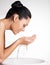 Smiling woman washing her clean face with water