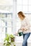 Smiling woman watering plant at home