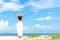 Smiling woman wearing fashion white dress summer walking on the sandy ocean beach, beautiful blue sky background. Happy woman enj