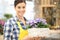 Smiling woman with wicker basket full of violet primrose flowers, spring concept