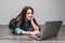 Smiling woman working on laptop on floor