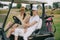 smiling women in caps sitting in golf cart and looking