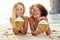 Smiling women drinking from coconuts while suntanning on a beach