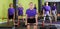 Smiling women in identical blue T-shirts training with bars