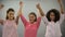 Smiling women with pink ribbon raising hands up, fighting against breast cancer