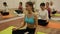 Smiling women practice yoga on rugs in a sports hall