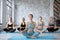 Smiling women and their teacher practicing yoga in gym. Relaxation and meditation