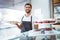 Smiling worker holding pastry behind the counter