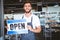 Smiling worker putting up open sign