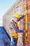 Smiling worker in reflective vest and hardhat working with spirit level