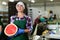 Smiling workwoman of fruit sorting factory standing with half of watermelon