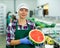 Smiling workwoman of fruit sorting factory standing with half of watermelon