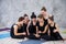 Smiling yogi girl exercising, having a break at class, group of friends watching on the phone