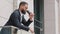 Smiling young african american corporation employee, manager, businessman drinking coffee on balcony during break