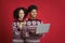 Smiling young african american couple in identical Christmas sweaters, guy typing on laptop