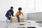 Smiling young african american family preparing for move, stack cardboard boxes for things in living room interior