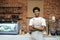 Smiling young african american guy in apron, with crossed hands near bar counter with coffee equipment