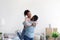 Smiling young african american husband hugs and lifts his wife in new apartment with cardboard boxes