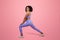 Smiling young african american lady in sportswear doing leg stretching exercise, enjoy sport