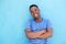 Smiling young african american man leaning against blue wall