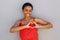 Smiling young african american woman with heart shape hand sign