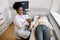 Smiling young African woman doctor using ultrasound probe on the wrist of young Caucasian woman patient, lying on the