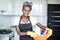 Smiling young african woman holding basket with cleaning equipment at hause