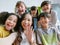 Smiling young Asian teacher making selfie with her schoolchildren in classroom. Elementary school,technology, children and people