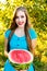 Smiling young attractive girl holding half of watermelon