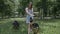 Smiling young attractive woman playing and training the gnintsi shepherd in the park in summer, feeds the dog a banana