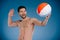 smiling young bare chested throwing beach ball and looking away