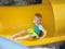 Smiling Young boy riding down a yellow water slide