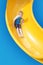 Smiling Young boy riding down a yellow water slide